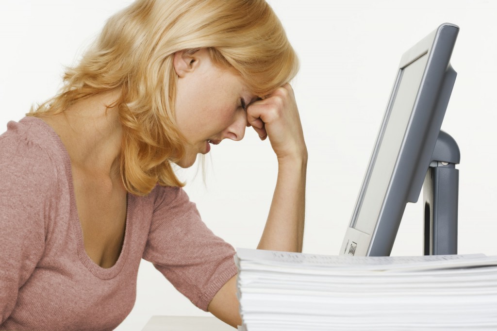 Frustrated Woman at Computer With Stack of Paper